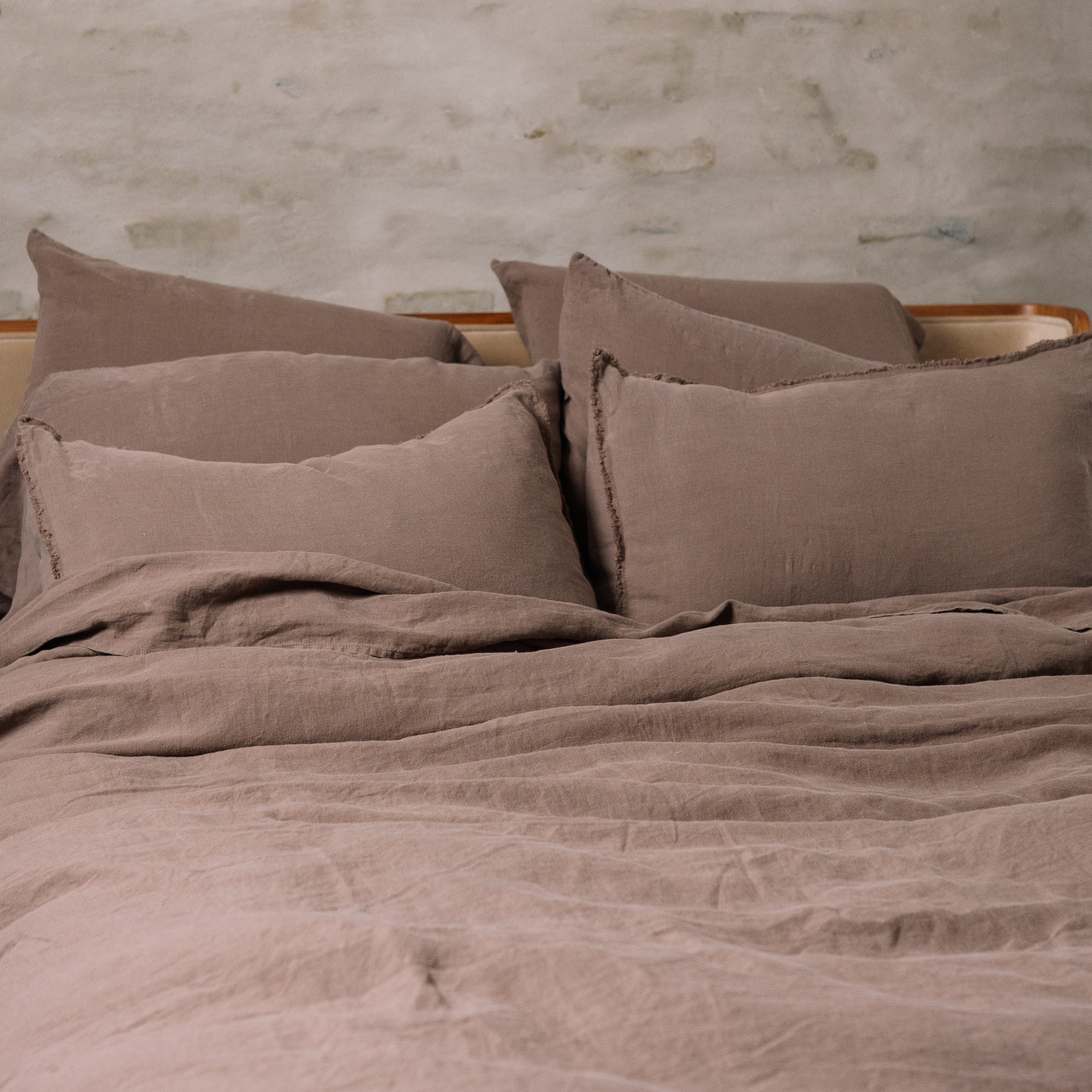 Multiple basic linen LEWSII pillowcases laying on a bed in Cappuccino color