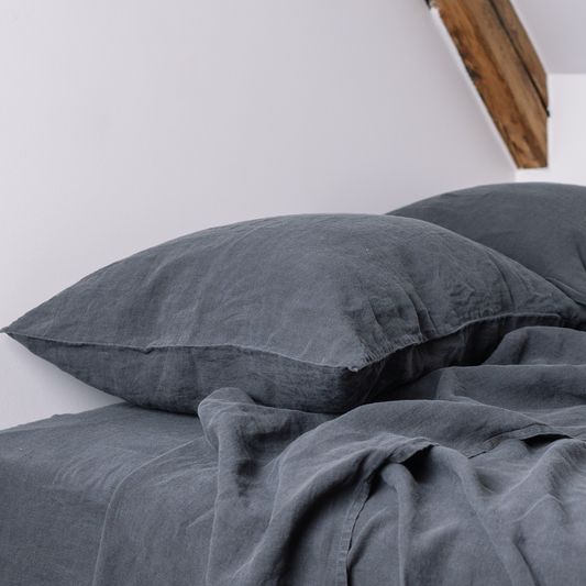Two LEWSII pillowcases on a bed in a dark grey color