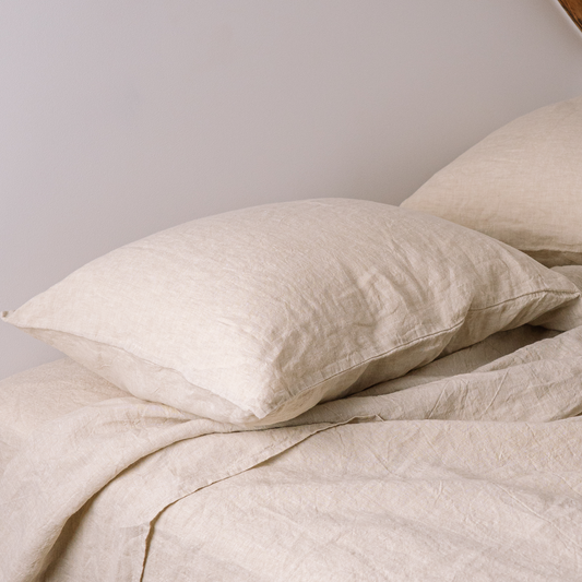 Two LEWSII pillowcases on a bed in a Sandy color